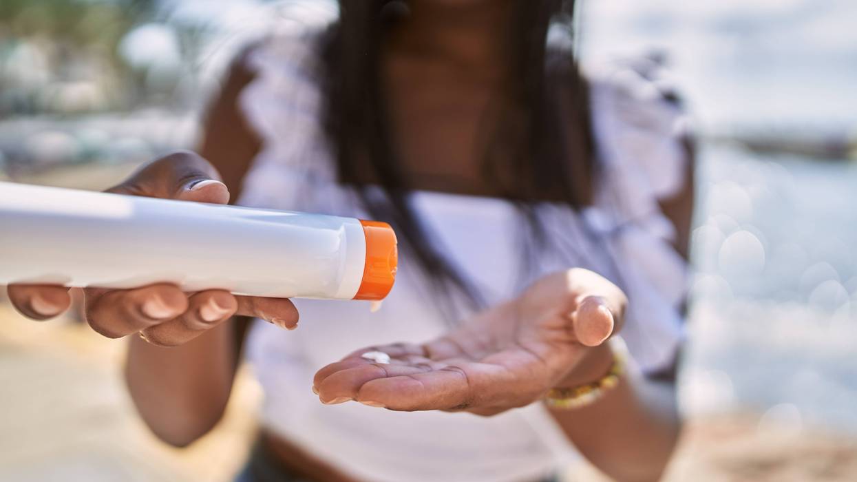 Young african american girl using sunscreen lotion at the beach.