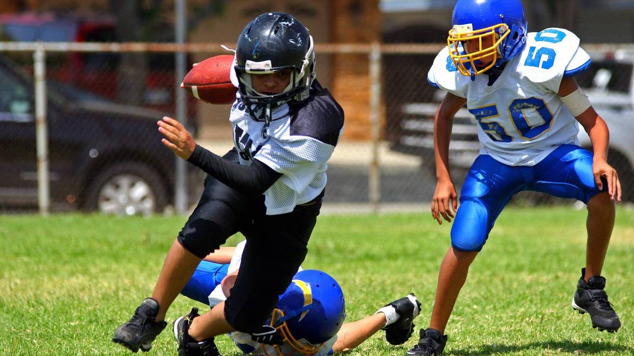 Young american football player running back breaking away from an attempted tackle. All logos and trademarks from uniforms, helmets and cleats have been removed in Photoshop