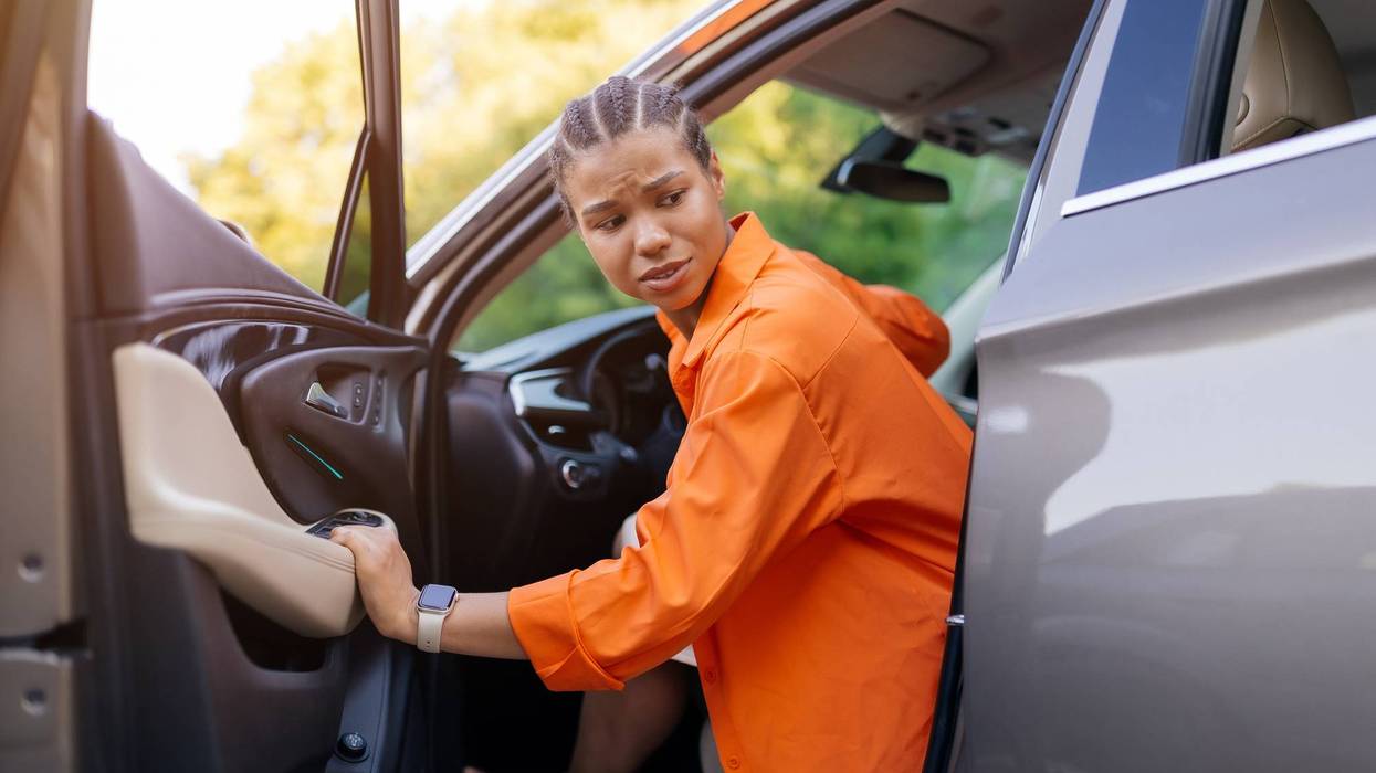 Young black woman stepping out of car with concerned facial expression. Possibly confused, surprised or reacting to something unexpected, closeup