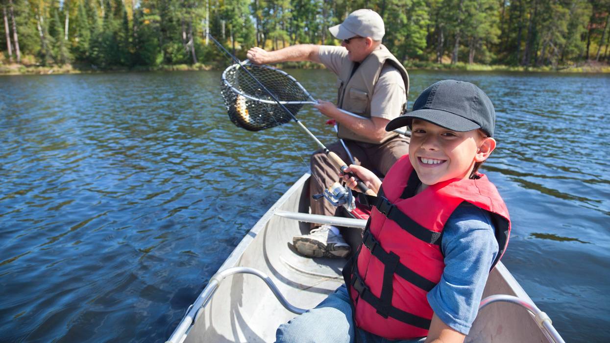 Young boy fishes with dad on the lake