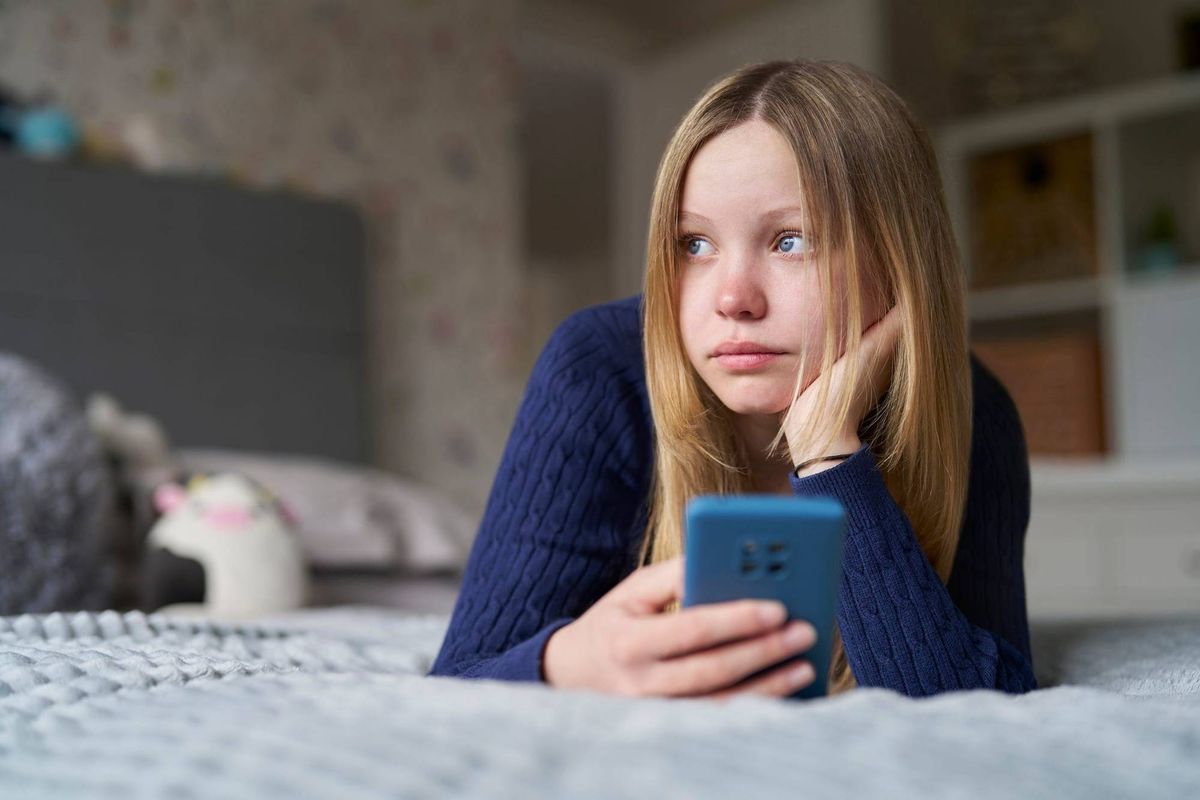 young girl on bed with cell phone