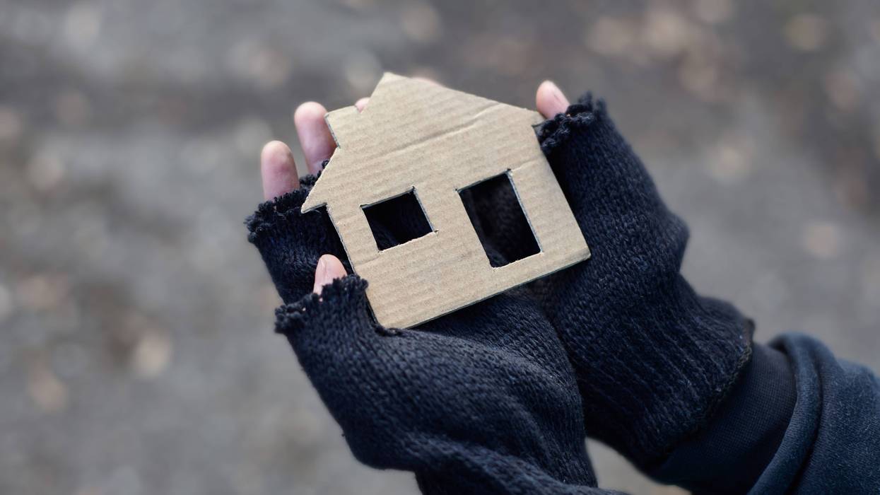 young homeless boy holding a cardboard house