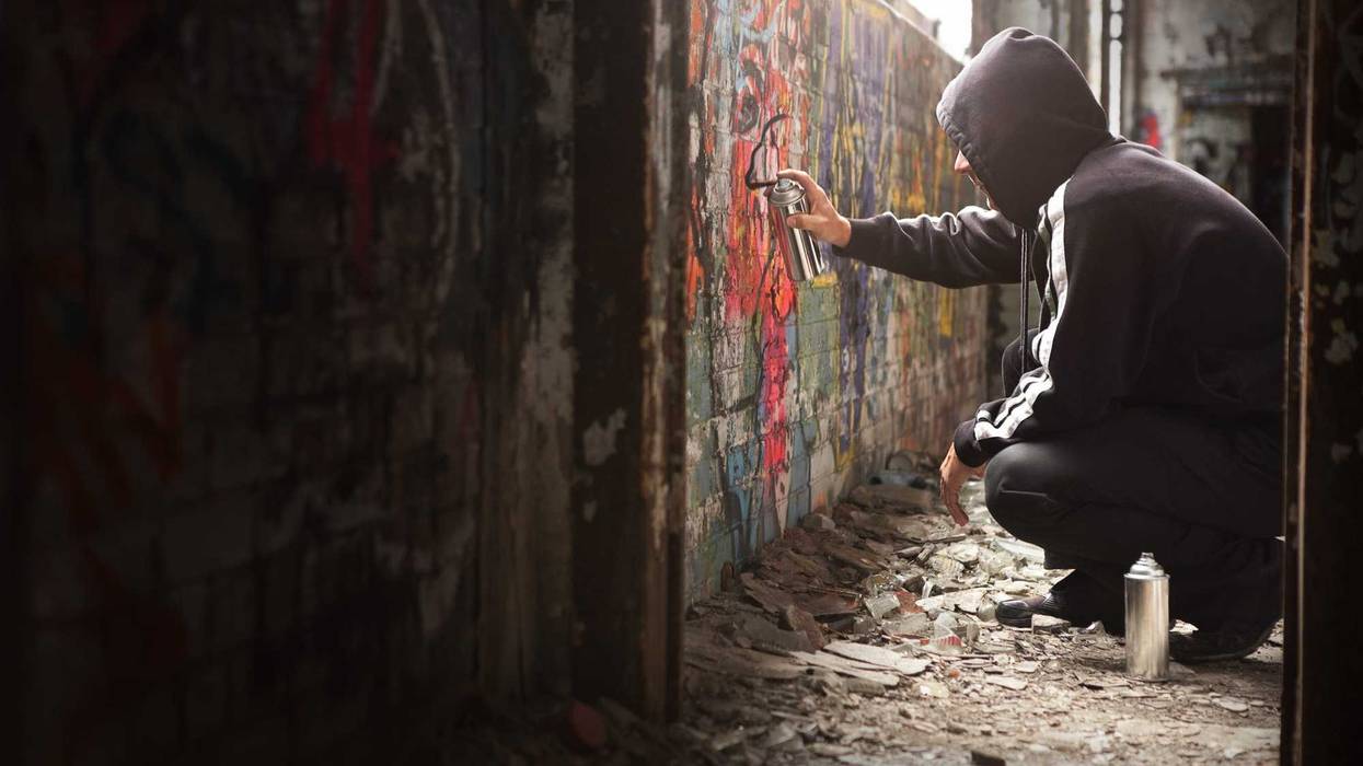Young kid spray painting a wall.