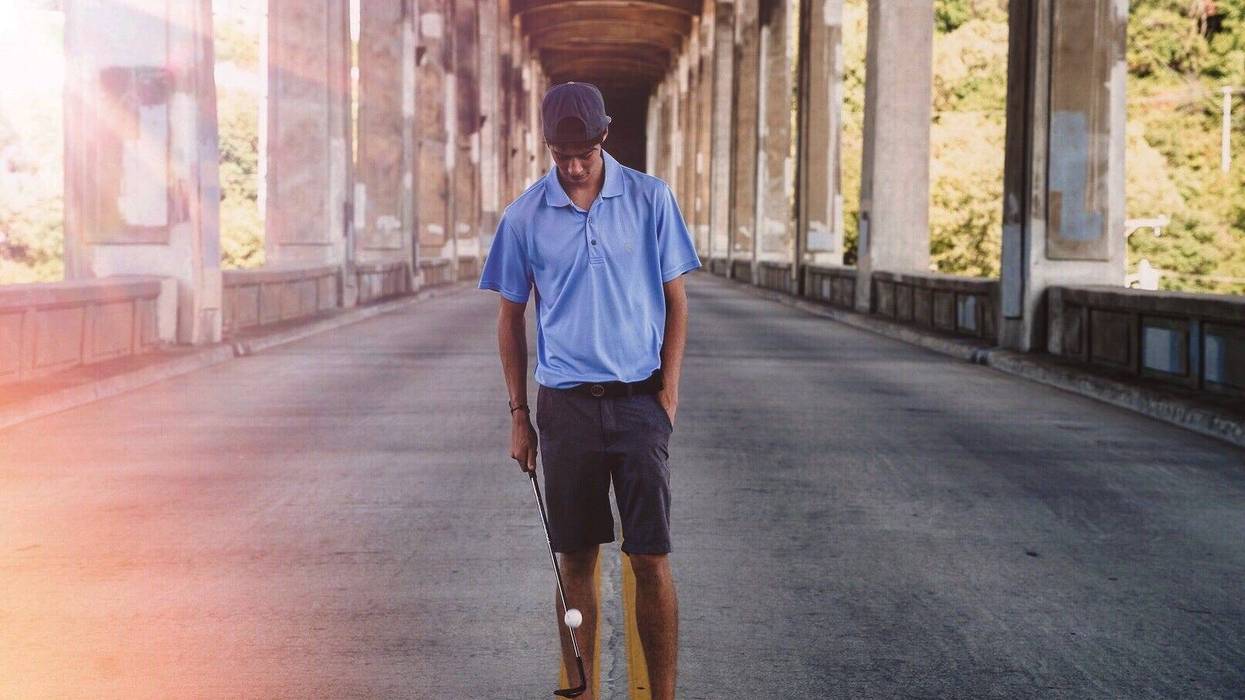 young man balancing ball on golf club