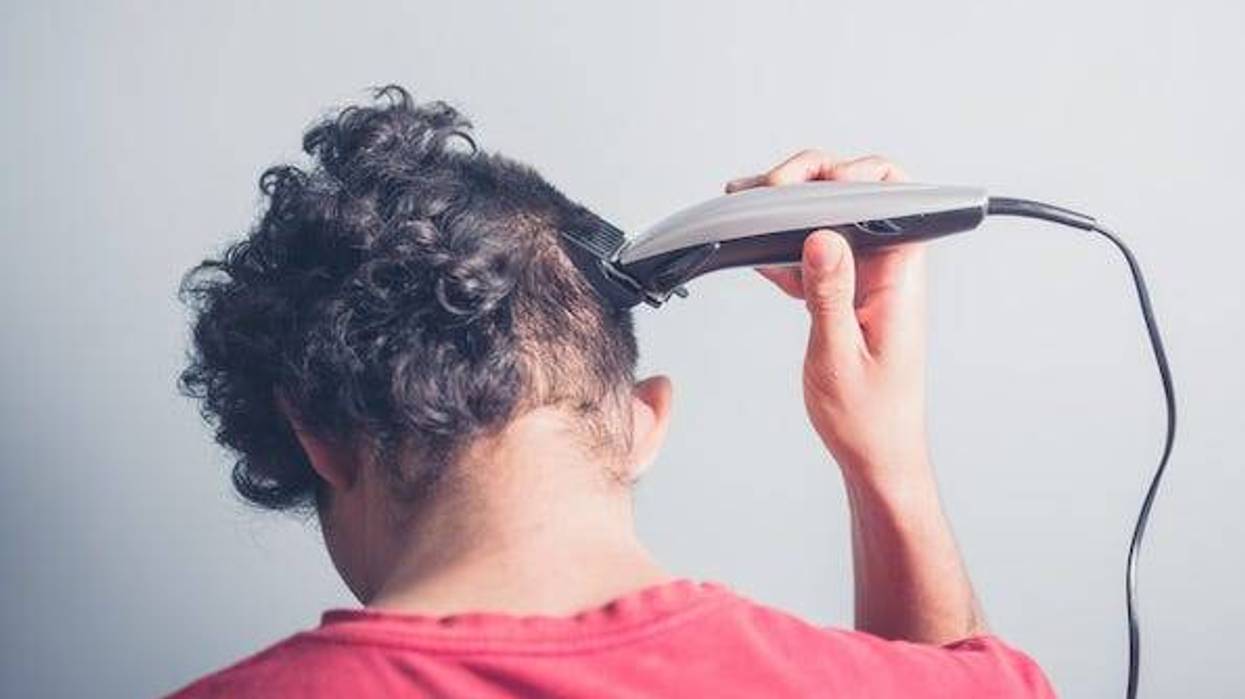 Young man cutting his hair at home