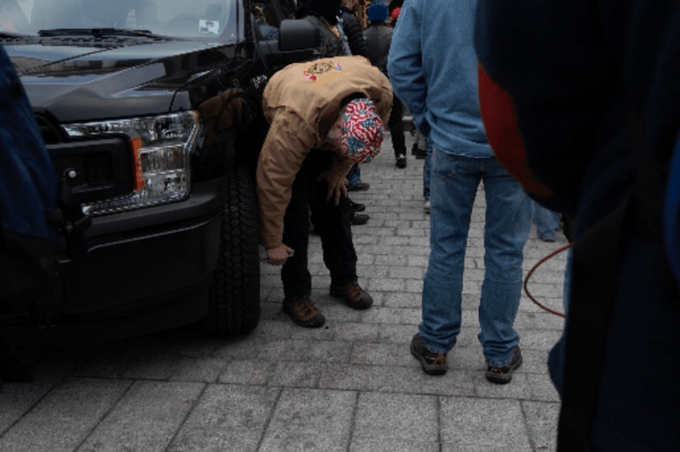 Young popping the tire of a government vehicle.
