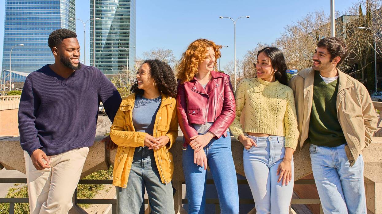 Young students talking and leaning on a bridge railing in the city