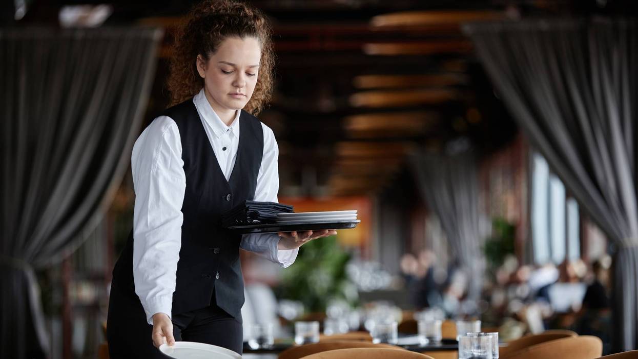 Young woman as female server setting table in restaurant preparing for opening