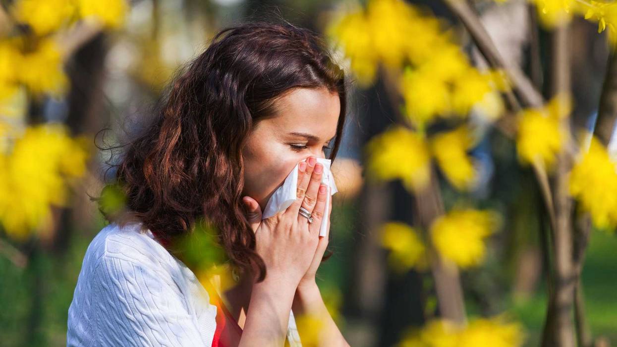 Young woman blowing her nose while being in the nature