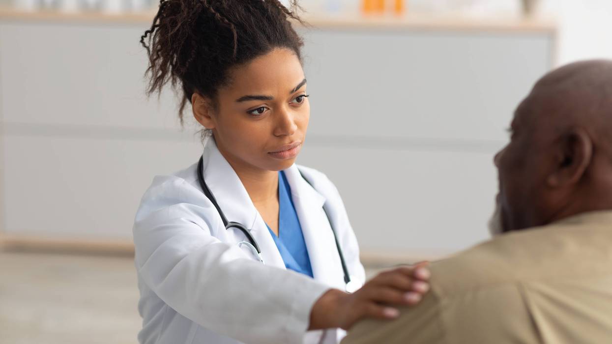 young woman doctor puts her hand on a patients shoulder