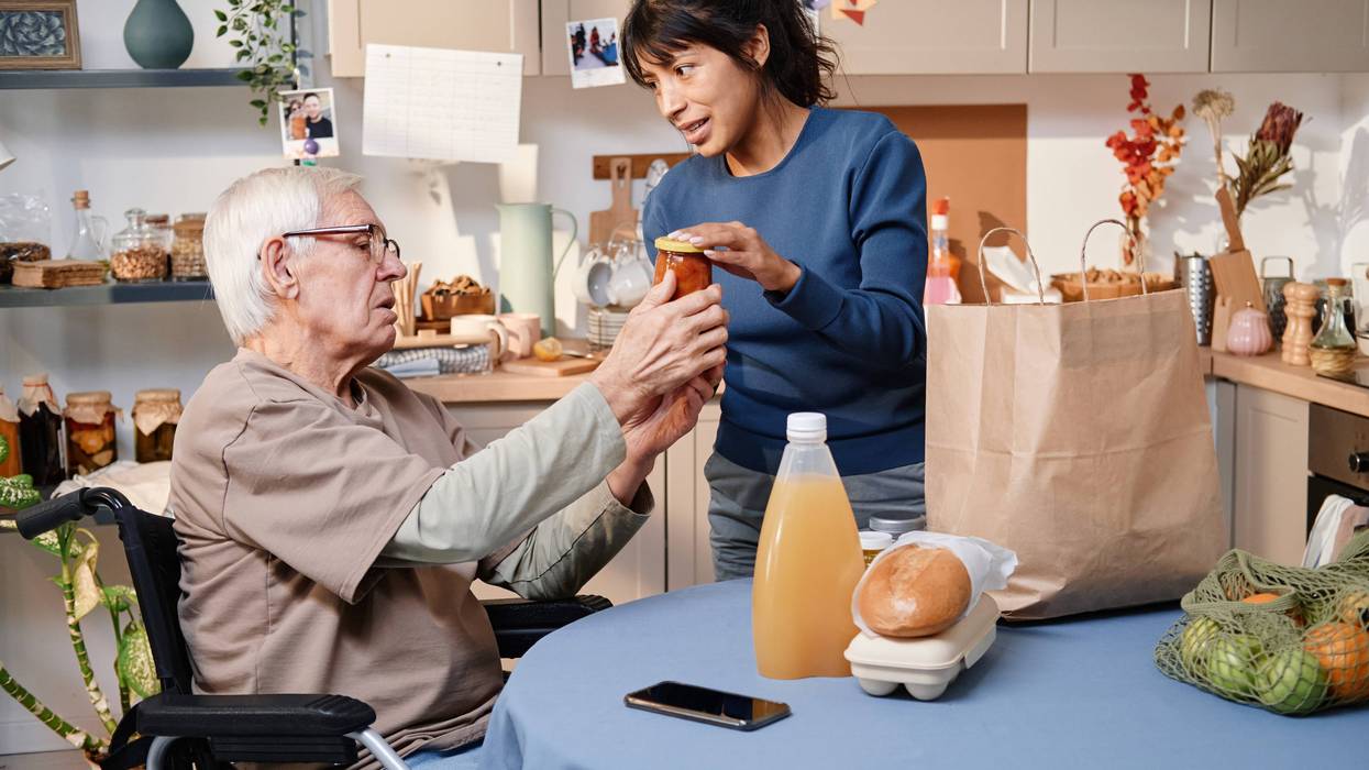 young woman helping an old man unpack groceries
