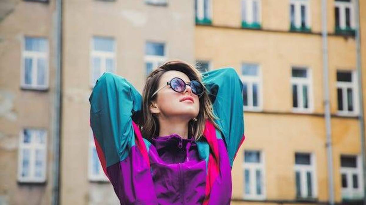 Young woman in 90s jacket posing in front of building