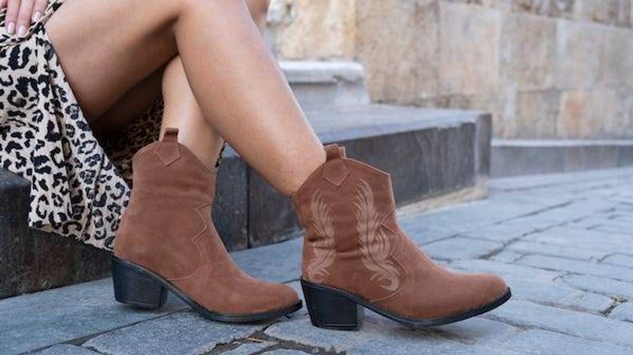 Young woman in cowboy boots sits on the street