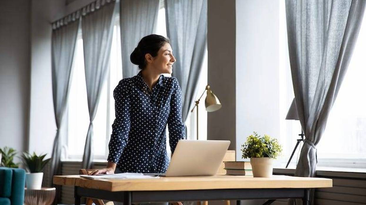 Young woman looking out window of home office