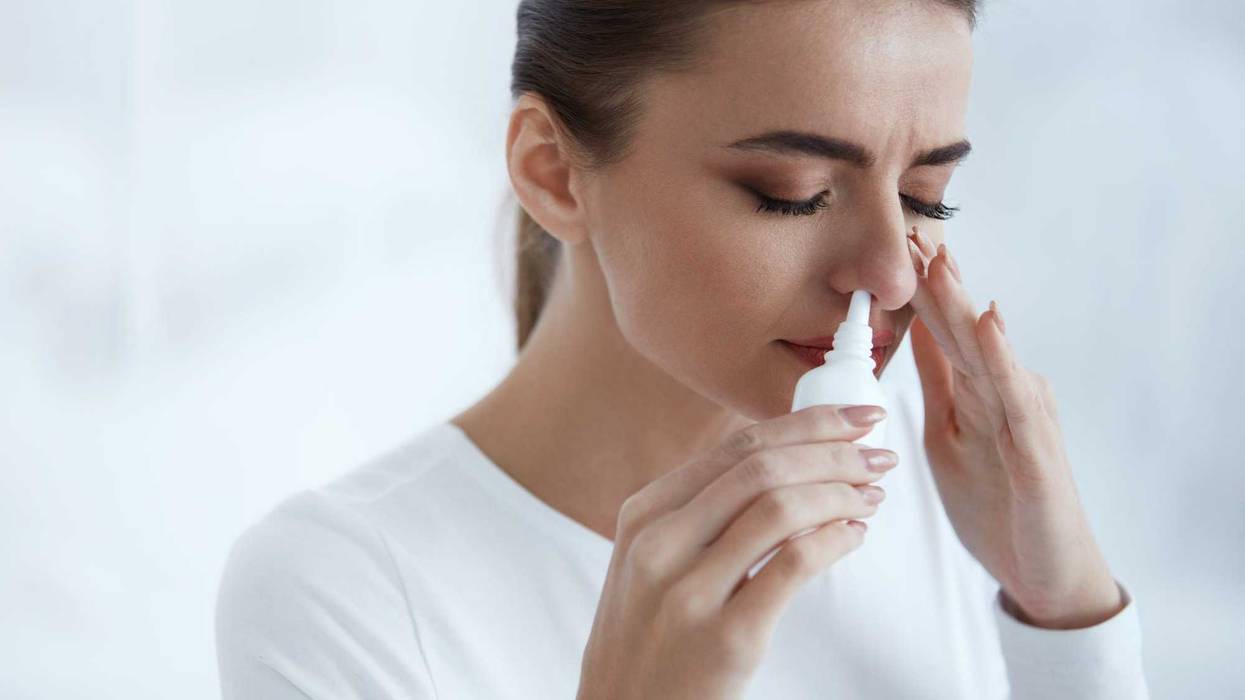 Young woman uses nasal spray while stressed.