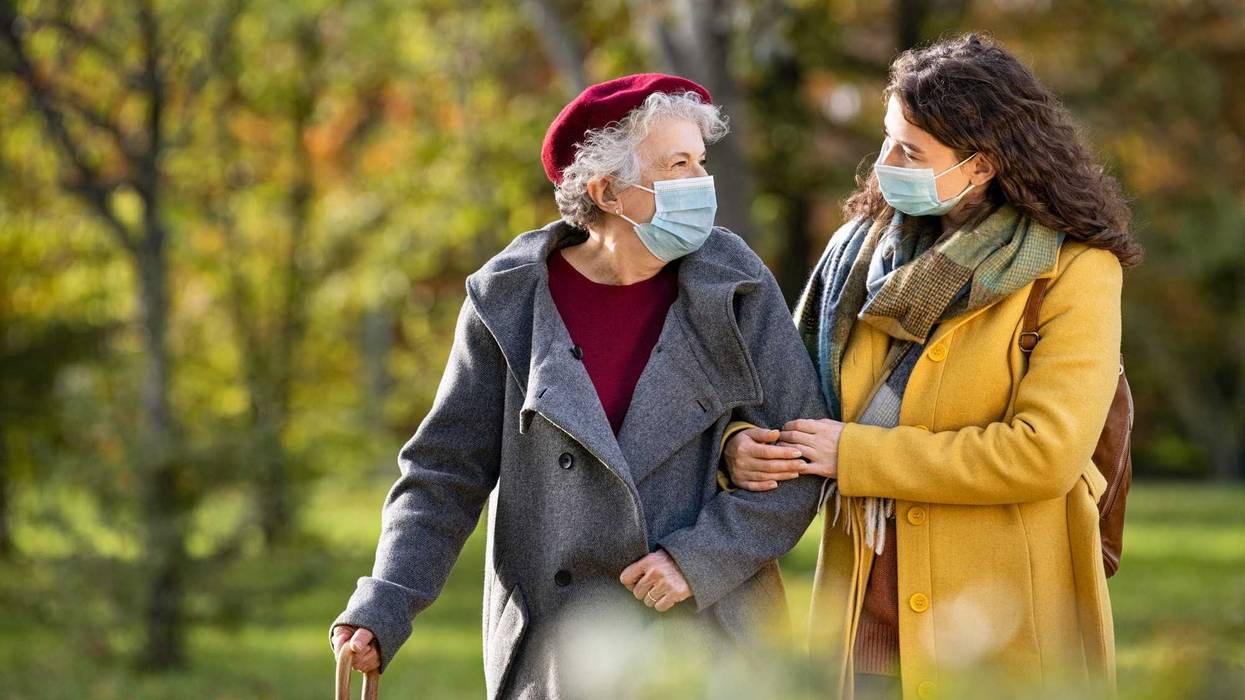 Younger woman helping older woman walk outside stock photo.